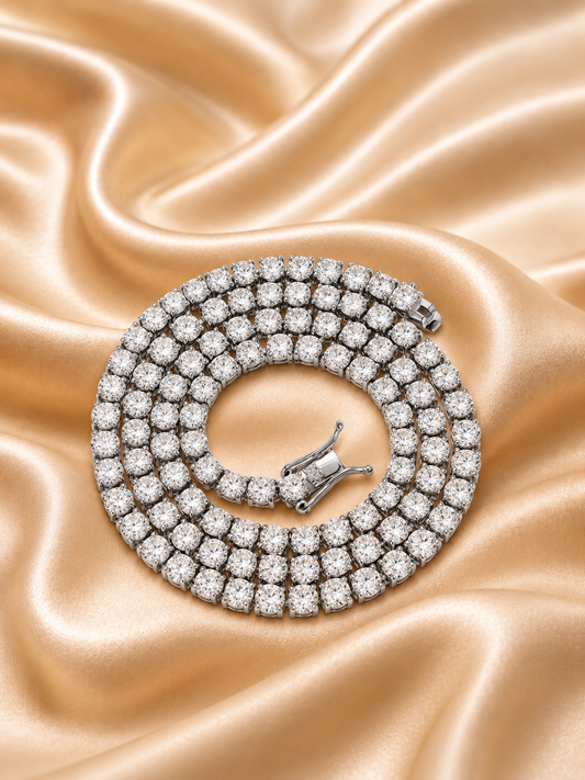 A coiled diamond tennis necklace with a silver-toned clasp, displayed on a draped champagne satin fabric background.