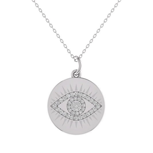 A silver-toned circular pendant necklace featuring an evil eye design set with clear stones, suspended from a delicate chain against a plain white background.