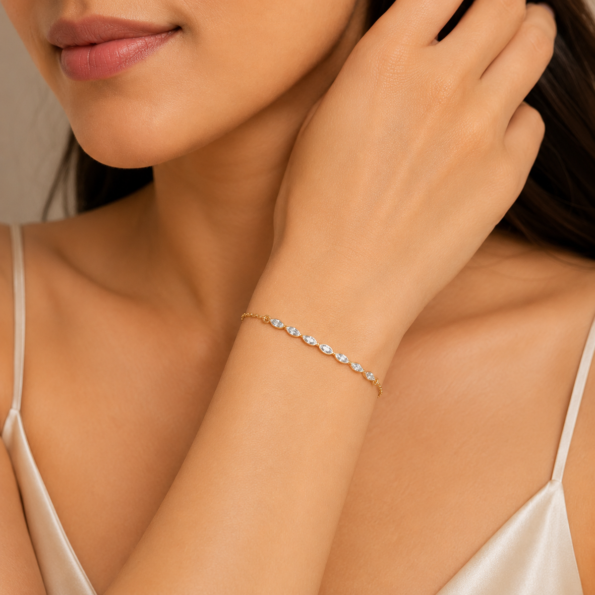 A delicate gold chain bracelet with small clear gemstones worn on a woman's wrist, shown in a close-up lifestyle shot.