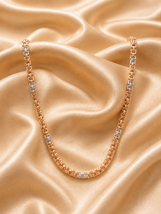 A rose gold tennis necklace with alternating clear gemstone links, draped elegantly on a draped champagne satin fabric background.